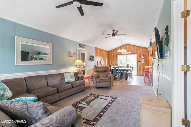 living room with wood walls, ceiling fan with notable chandelier, light colored carpet, and vaulted ceiling