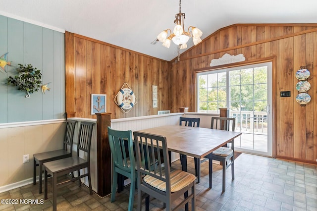 tiled dining space featuring wood walls, a chandelier, and lofted ceiling