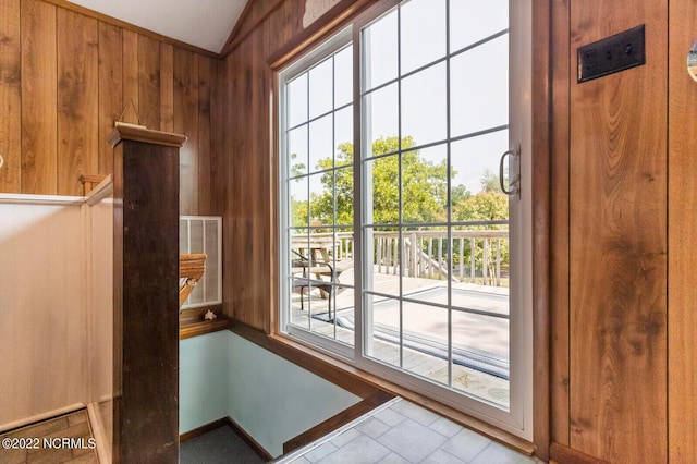 doorway to outside with light tile flooring, wooden walls, and vaulted ceiling