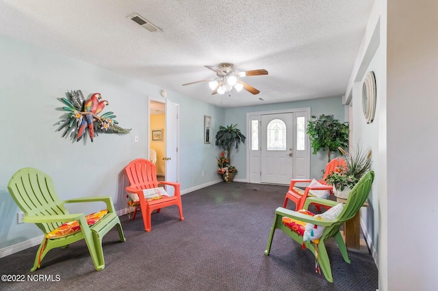 living area with ceiling fan and a textured ceiling