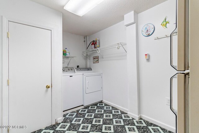 laundry area with a textured ceiling, dark tile flooring, and independent washer and dryer