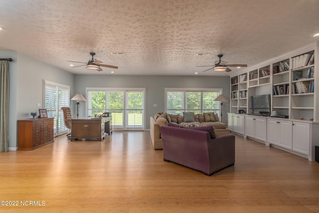 living room with ceiling fan, light hardwood / wood-style flooring, and a textured ceiling