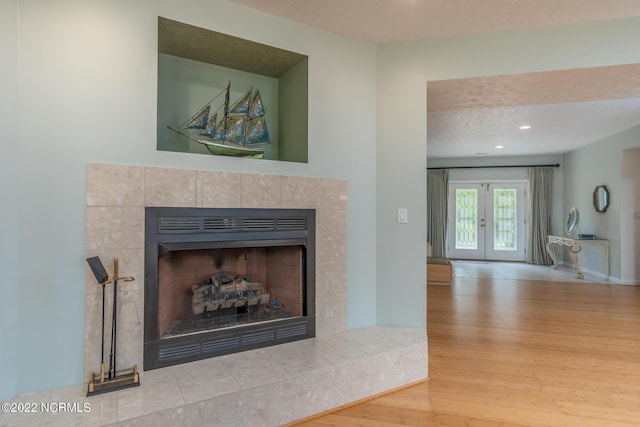 interior details with a fireplace, a textured ceiling, light hardwood / wood-style flooring, and french doors