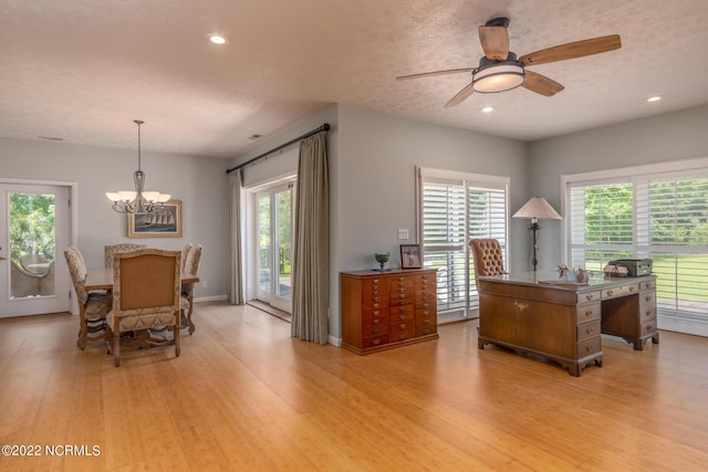 home office featuring a healthy amount of sunlight, light hardwood / wood-style floors, and ceiling fan with notable chandelier