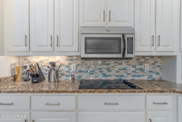 kitchen with black electric stovetop, tasteful backsplash, white cabinetry, and dark stone counters