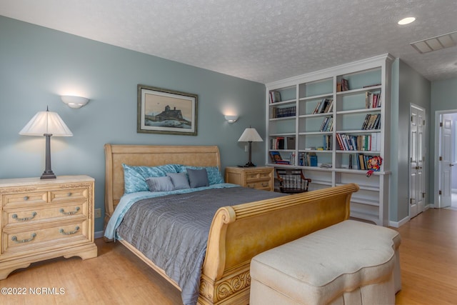 bedroom with a textured ceiling and light hardwood / wood-style floors