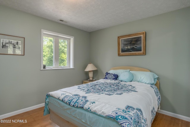 bedroom featuring a textured ceiling and light hardwood / wood-style flooring