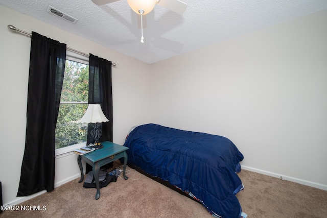 carpeted bedroom with ceiling fan and a textured ceiling