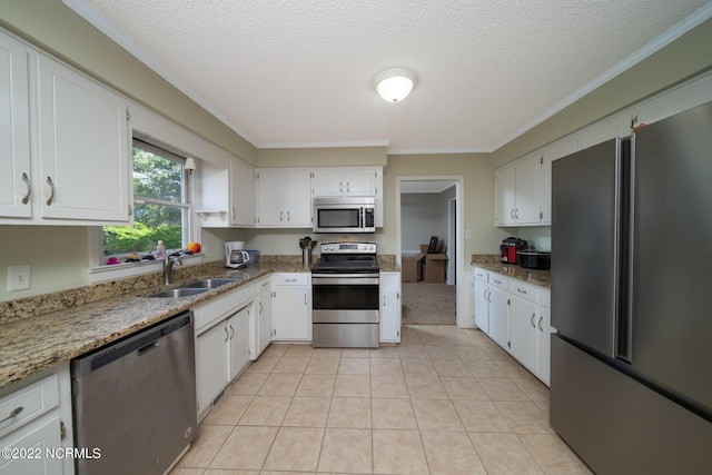 kitchen with stainless steel appliances, white cabinetry, light tile floors, and light stone countertops