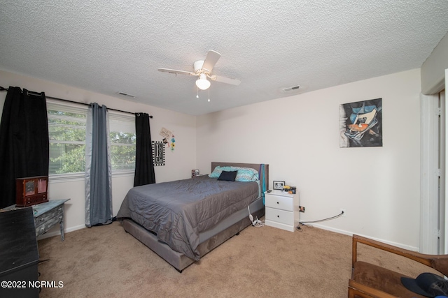 bedroom featuring light carpet, ceiling fan, and a textured ceiling