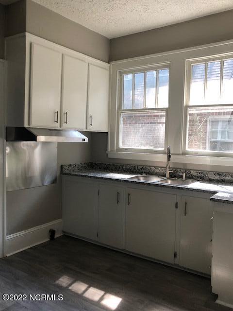 kitchen featuring white cabinetry, a textured ceiling, dark wood-type flooring, and sink