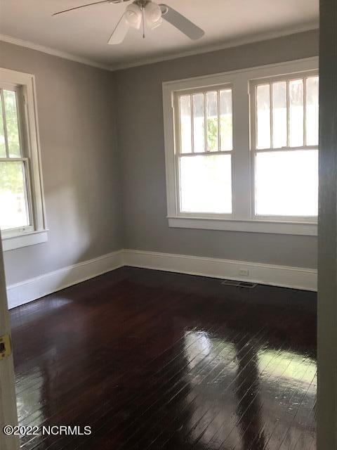 spare room with ceiling fan, dark wood-type flooring, and ornamental molding