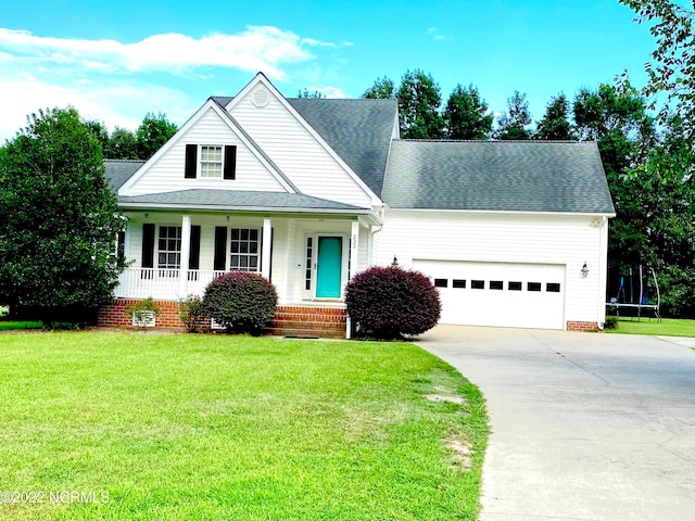 view of front of home with a front yard, a porch, a trampoline, and a garage