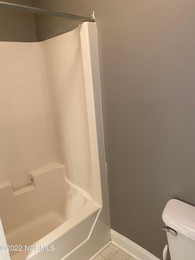 bathroom with bathing tub / shower combination, tile floors, and toilet