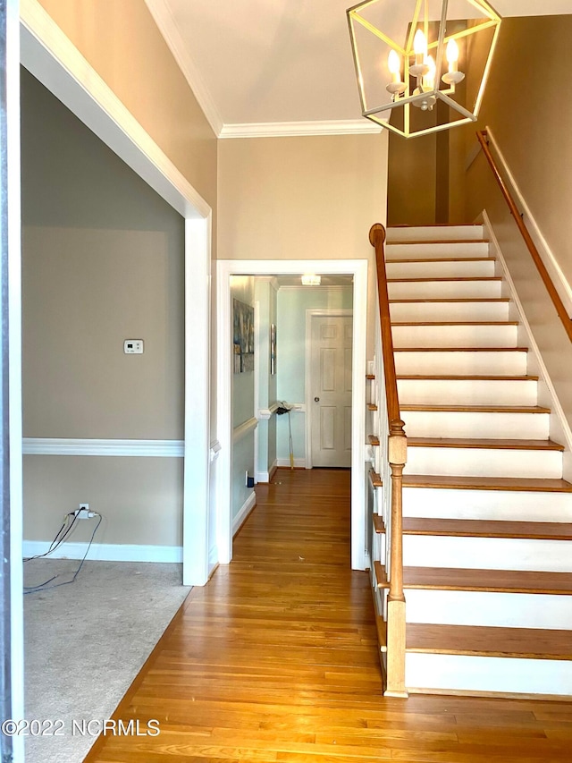 stairs featuring a chandelier, light wood-type flooring, and crown molding