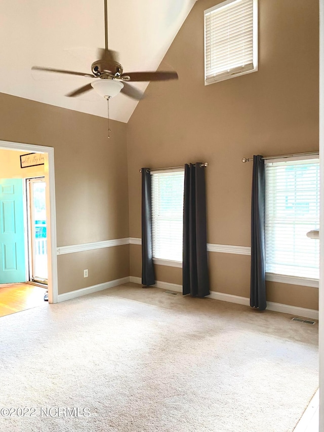 carpeted empty room featuring ceiling fan and high vaulted ceiling