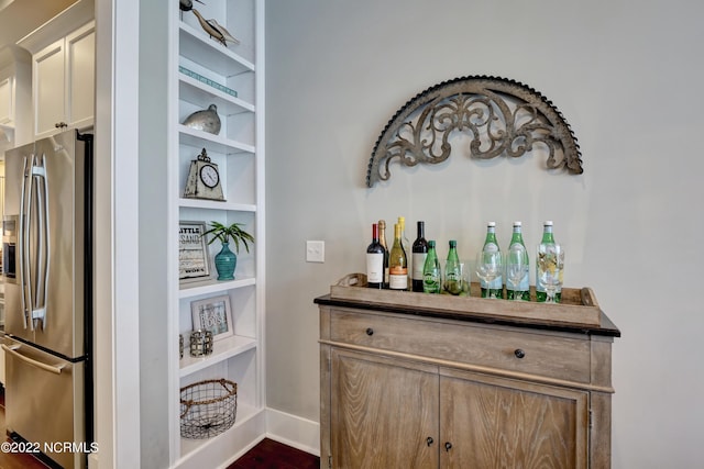 bar featuring stainless steel refrigerator with ice dispenser