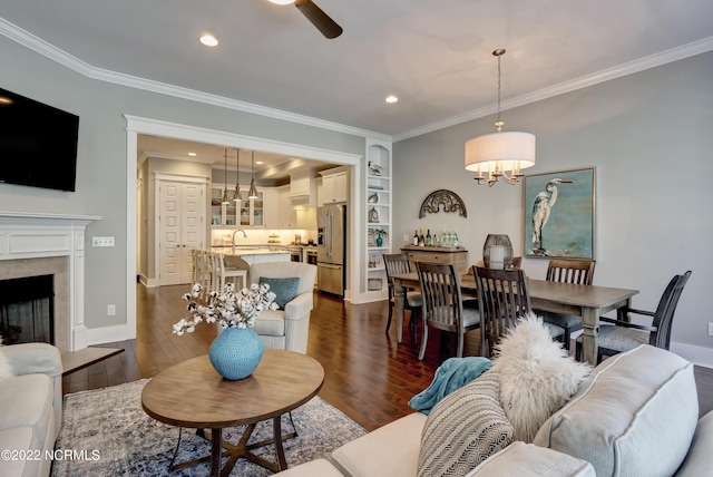 living room with dark wood-type flooring, ornamental molding, and ceiling fan with notable chandelier