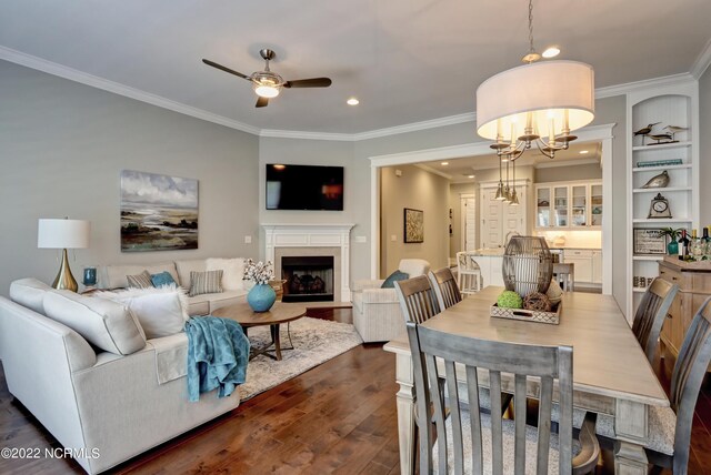 dining area with ornamental molding, dark hardwood / wood-style floors, and ceiling fan with notable chandelier