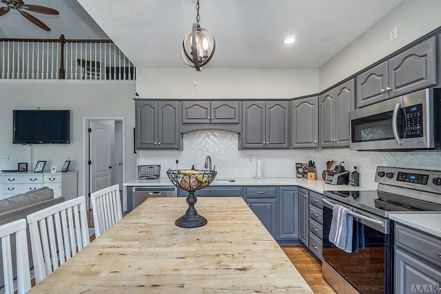 kitchen featuring appliances with stainless steel finishes, decorative light fixtures, tasteful backsplash, and ceiling fan with notable chandelier