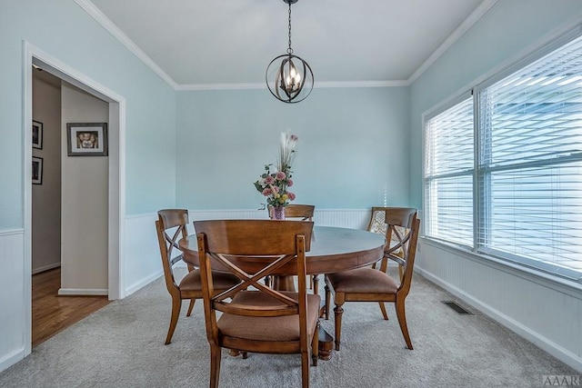 dining room featuring a notable chandelier, crown molding, and light colored carpet