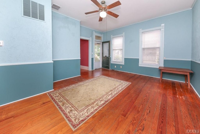 empty room with dark hardwood / wood-style floors, ornamental molding, and ceiling fan