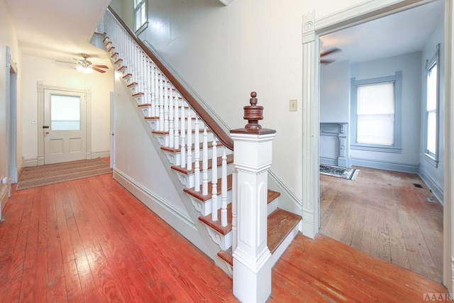 staircase with ceiling fan and light hardwood / wood-style floors