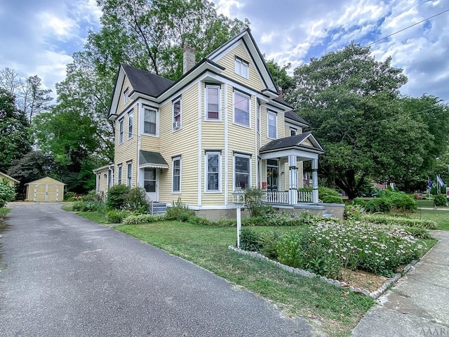 view of front facade featuring a front lawn, a storage shed, and a porch