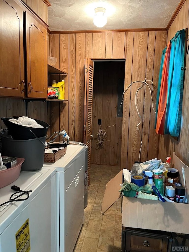 laundry area with wood walls, crown molding, light tile floors, washer and dryer, and cabinets