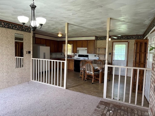 kitchen featuring carpet, a center island, white appliances, ceiling fan with notable chandelier, and hanging light fixtures