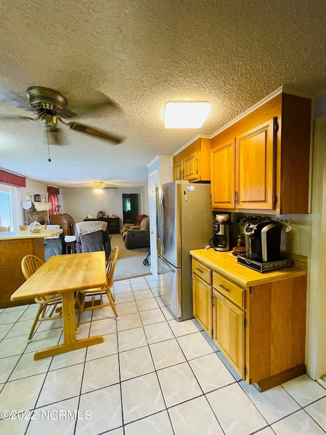 kitchen with stainless steel fridge, ceiling fan, a textured ceiling, and light tile floors