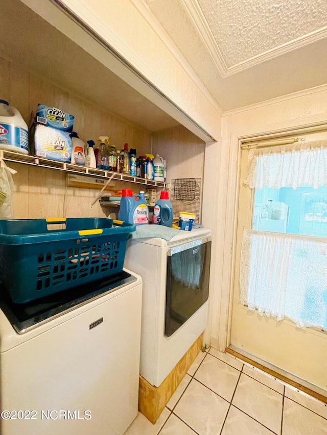 laundry room with washer and clothes dryer, a textured ceiling, light tile flooring, and ornamental molding