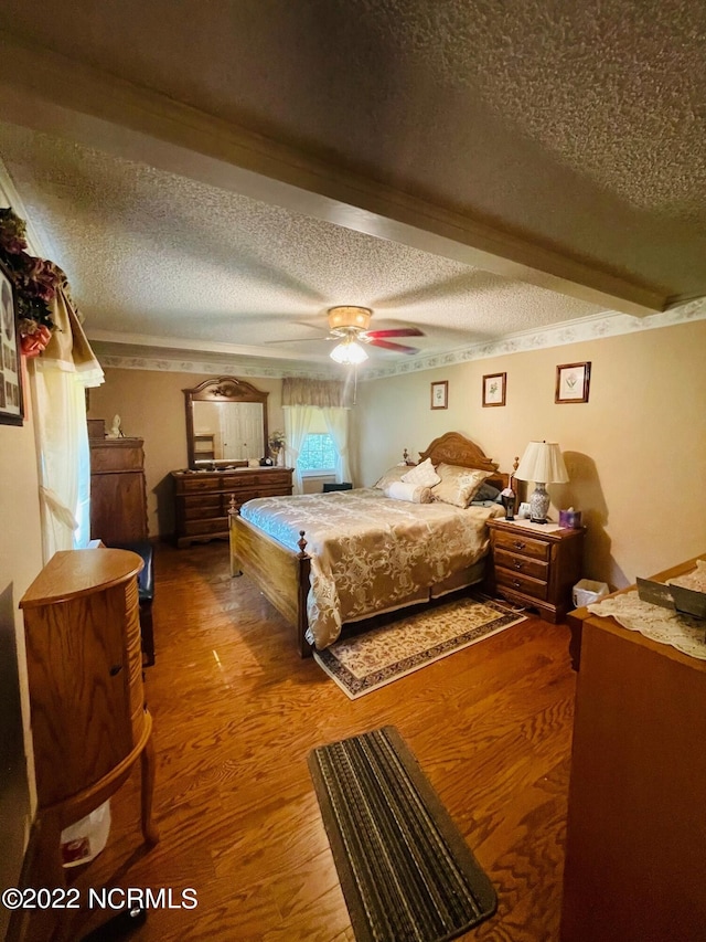 bedroom with a textured ceiling, dark hardwood / wood-style floors, ceiling fan, and beam ceiling