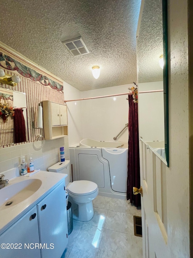 bathroom with toilet, vanity, backsplash, a textured ceiling, and tile floors