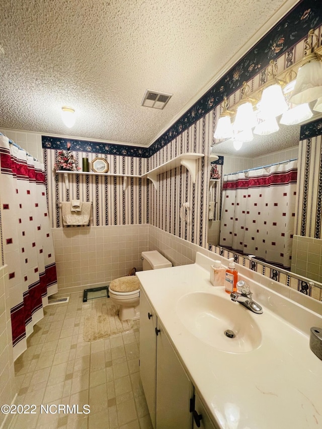 bathroom with vanity, tile walls, tile floors, a textured ceiling, and toilet