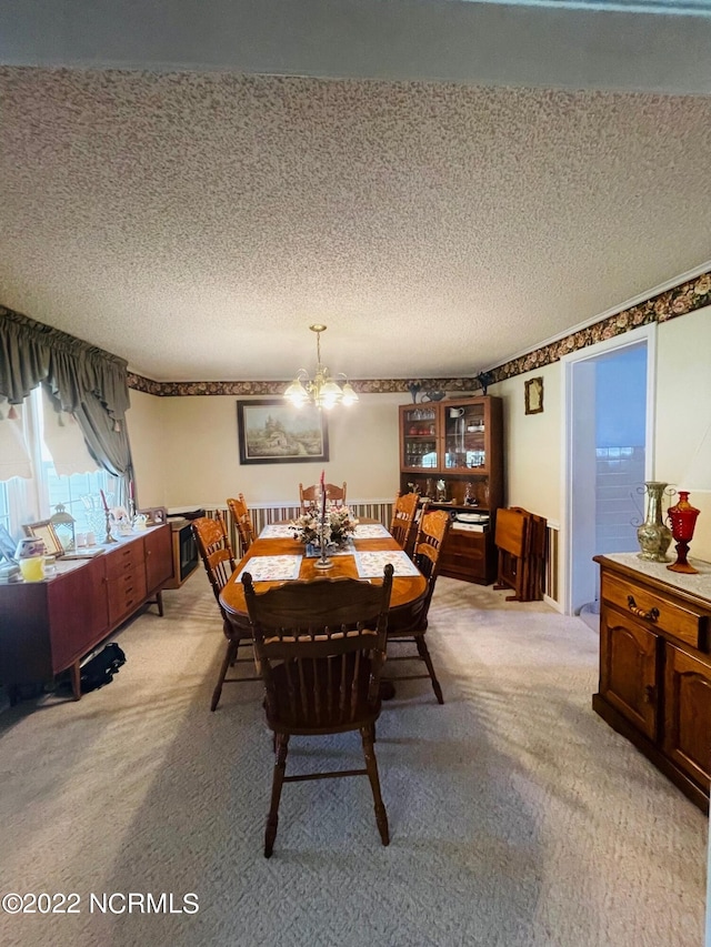 carpeted dining space featuring a notable chandelier and a textured ceiling