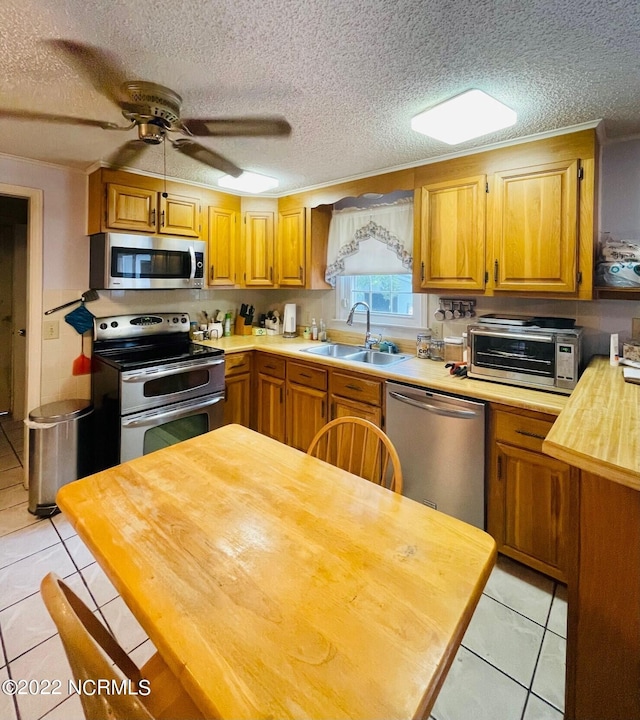 kitchen with light tile floors, stainless steel appliances, ceiling fan, and sink