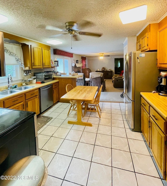 kitchen featuring light tile floors, appliances with stainless steel finishes, ceiling fan, and sink