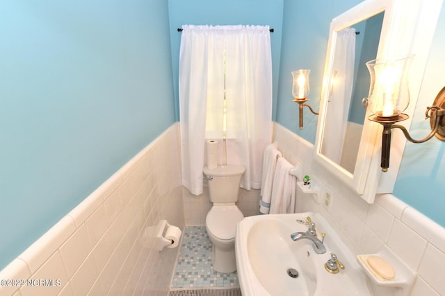 bathroom featuring toilet, tile walls, backsplash, tile floors, and sink