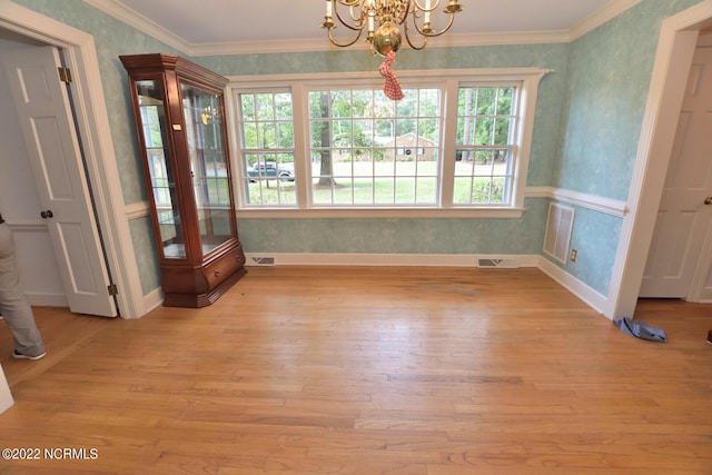 unfurnished dining area with crown molding, light hardwood / wood-style flooring, a wealth of natural light, and a chandelier