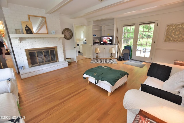 living room with a brick fireplace, light hardwood / wood-style flooring, french doors, and beam ceiling