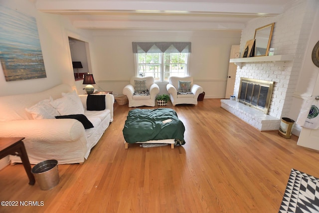 living room with a fireplace, beamed ceiling, and light wood-type flooring