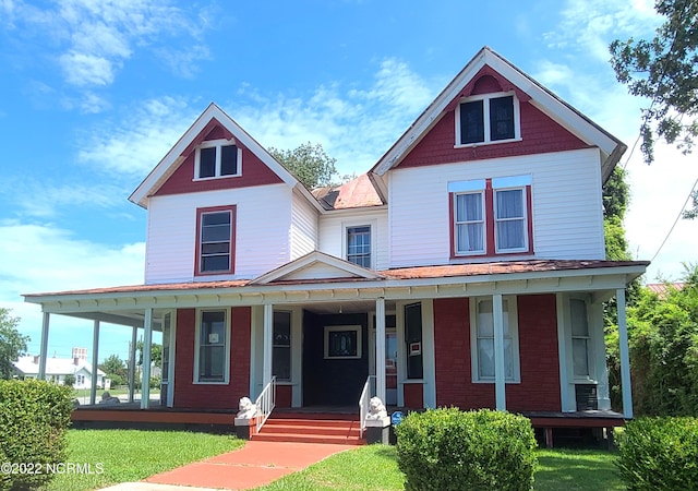 victorian-style house featuring a front yard and a porch