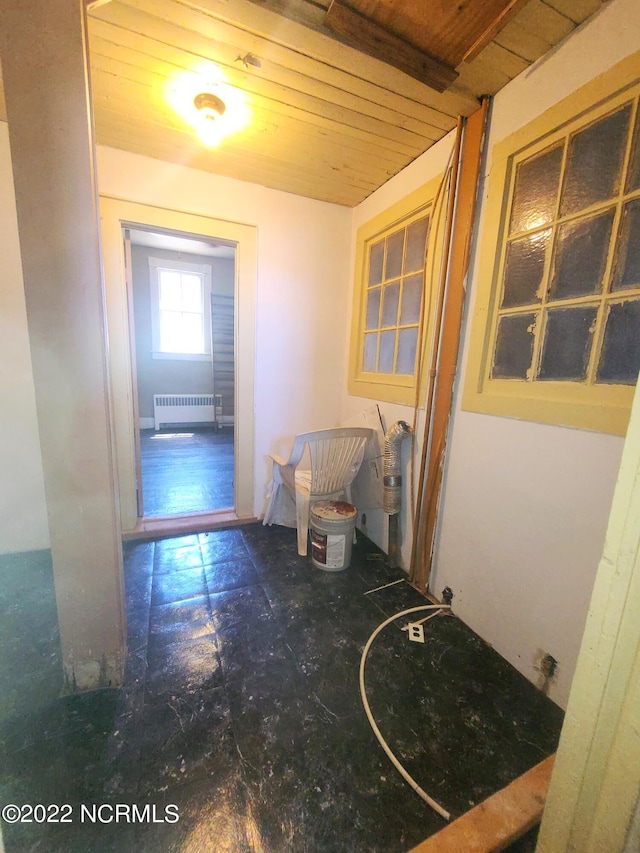 hallway featuring wood ceiling, dark tile flooring, and radiator