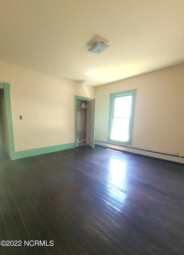 unfurnished room with a baseboard radiator and dark hardwood / wood-style floors