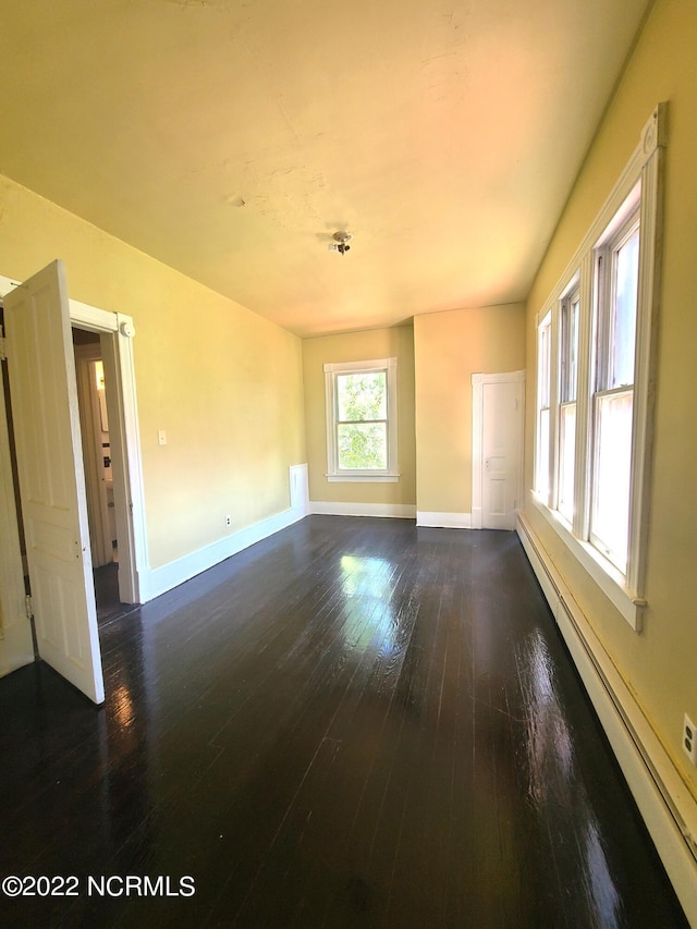 unfurnished living room with dark hardwood / wood-style flooring and a baseboard heating unit