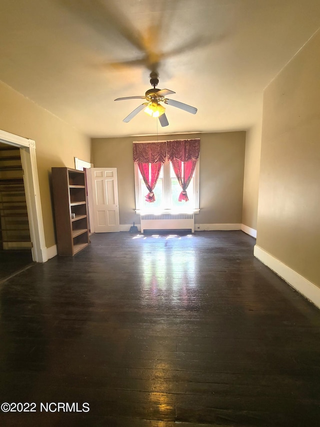 spare room with ceiling fan, radiator, and dark hardwood / wood-style floors