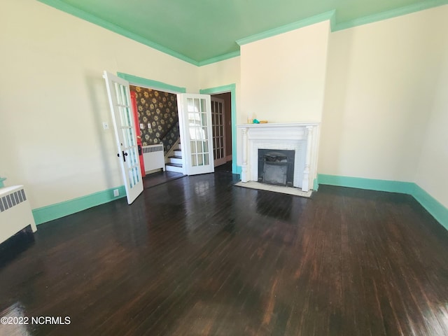 unfurnished living room with french doors, crown molding, dark hardwood / wood-style floors, and radiator heating unit