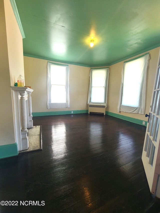 unfurnished living room featuring dark hardwood / wood-style floors, a healthy amount of sunlight, and radiator