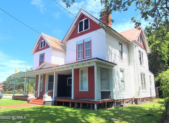 back of house featuring a lawn and a porch